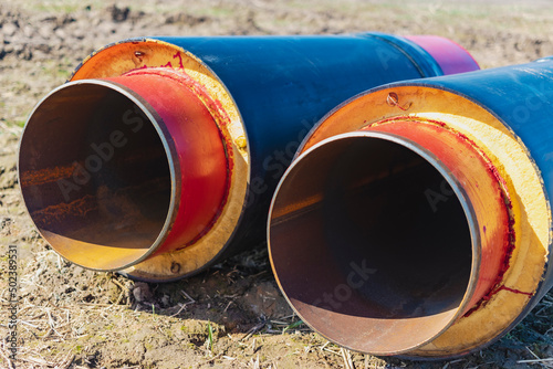 Insulated pipe. Large metal pipes with a plastic sheath at a construction site. Modern pipeline for supplying hot water and heating to a residential area. Close-up.