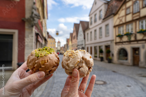 eating traditional schneeball snowball cake together the cake of the romantic Rothenburg ob der Tauber with timbered Fachwerkhaus syle houses in Bavaria Germany