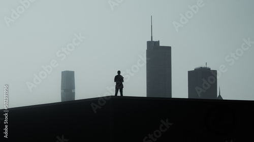 Obraz na plátně Scenic shot of a silhouette of a person standing on the rood and looking at the