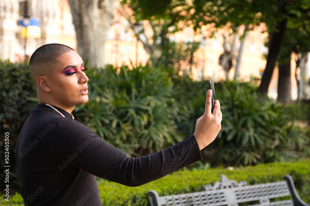 Non-binary and young person from South America is on holiday in Europe, the person is make up and wearing black clothes. He is visiting the city and takes pictures with his mobile phone. Travel Non-binary and young person from South America is on holiday in Europe, the person is make up and wearing black clothes. He is visiting the city and takes pictures with his mobile phone. Travel