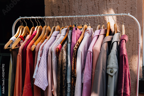 Tablou pe pânză Closeup shot of colorful fashionable clothes hanging on a rail outside a shop