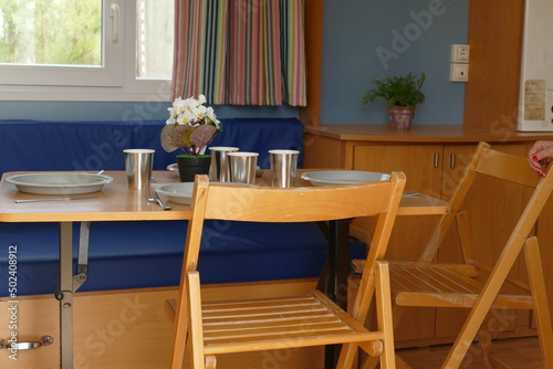 Elegante interior de un salon con la mesa puesta, adornado con flores, cortinas de colores, sillas de madera marrones