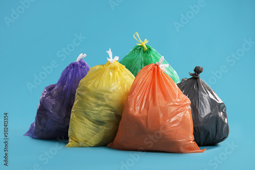 Trash bags full of garbage on light blue background