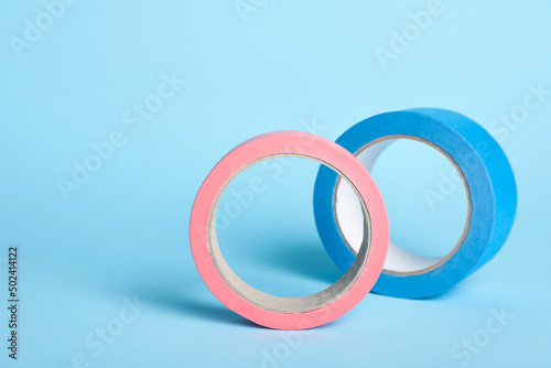 Two bright rolls of adhesive tape on light blue background
