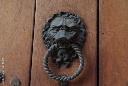 Closeup of a metallic knocker with a lion head on a wooden door in Cartagena, Colombia
