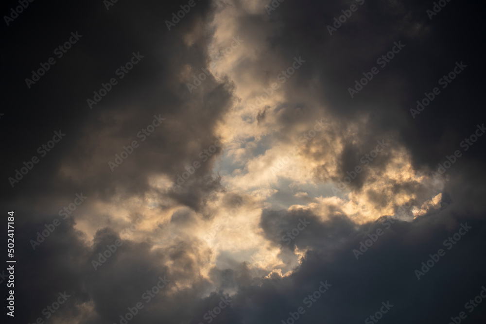 Dark gray clouds fly across the sky. Puffy fluffy grey clouds at spring day during sunset