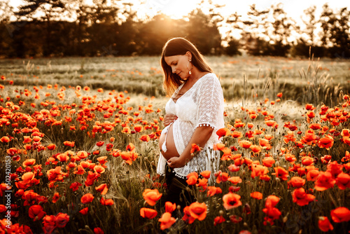 Pregnant model posing for a photoshoot in a field.
