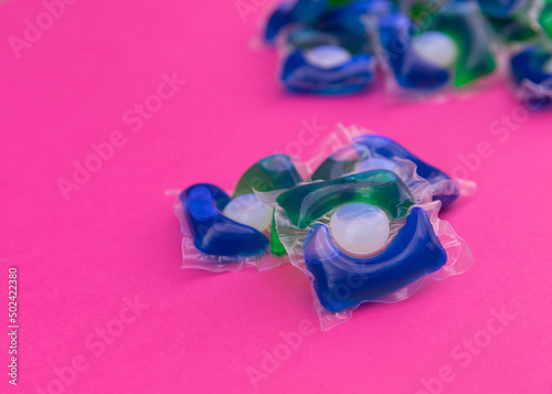 Capsule of gel for washing clothes in a washing machine with detergent on a pink background. View from above. Space for copy.Cleanliness concept. photo