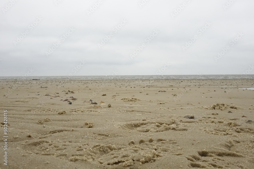 Sandy North Sea beach with footsteps at low tide (focus on front centre), cloudy spring day (horizontal), Sahlenburg, Lower Saxony, Germany Sandy North Sea beach with footsteps at low tide (focus on front centre), cloudy spring day (horizontal), Sahlenburg, Lower Saxony, Germany