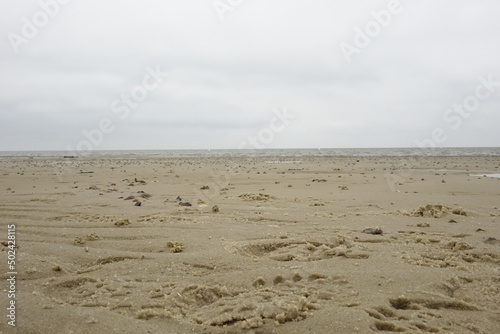 Sandy North Sea beach with footsteps at low tide (focus on front centre), cloudy spring day (horizontal), Sahlenburg, Lower Saxony, Germany