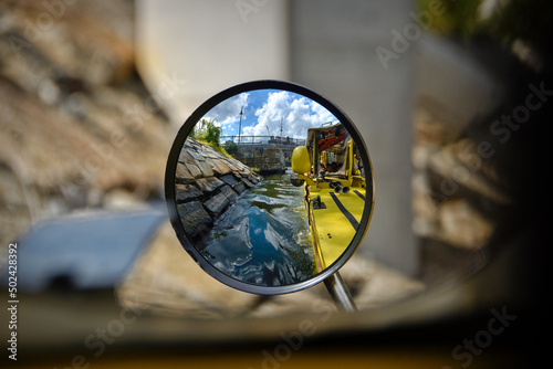 Closeup shot of a yellow boat in a canal seen in a side mirror of a vechicle photo