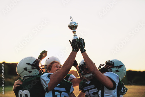 Fototapeta Cheering football team holding up a trophy