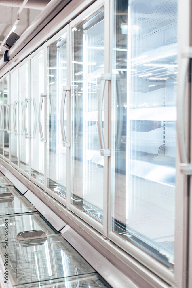 Empty refrigerator or freezer for food and grocery items in store. Selective focus, vertical photo. Empty refrigerator or freezer for food and grocery items in store. Selective focus, vertical photo.