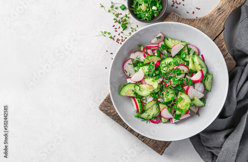 Summer vegetable salad with radish, cucumber and herbs on a gray background. Healthy, dietary salad. Top view, space to copy.