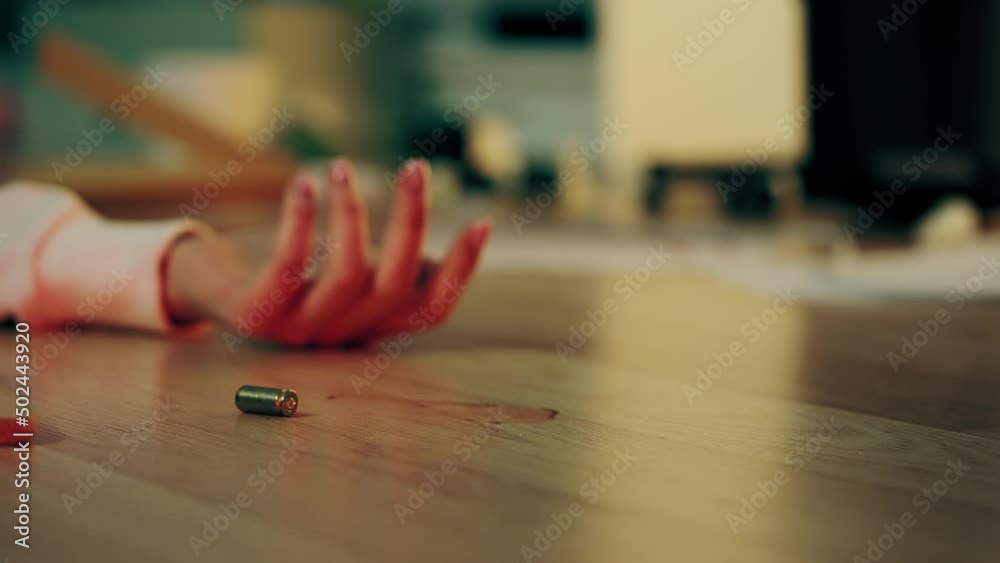 Close-up of woman shot in her apartment, bullet case falling on the floor