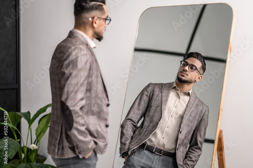 A good-looking young stylish man at the mirror
