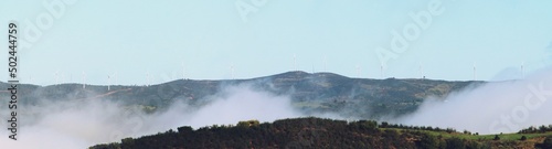 Aerogeneradores situados en lo alto de unas colinas. Aerogeneradores entre la niebla matutina en el pueblo de El Granado en Huelva, Andalucía, España. photo