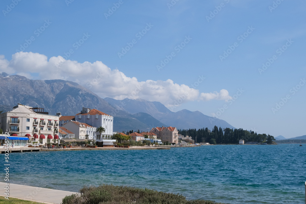houses on the shore of kotor bay, Tivat, Montenegro. clouds over mountains in blue sky around town, forest and sea port. beautiful nature landscape, paradise beach place. 