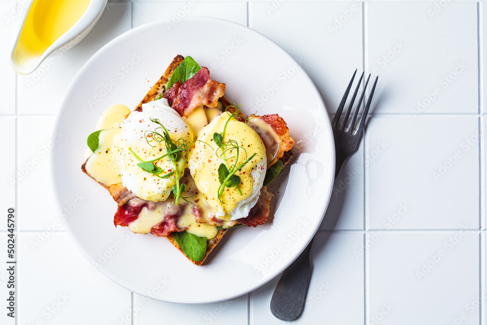 Eggs benedict on crispy toast with bacon and traditional hollandaise sauce. Delicious breakfast concept.
