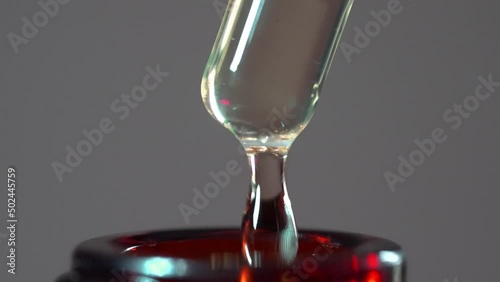 Drops of liquid being pumped into a brown bottle. 