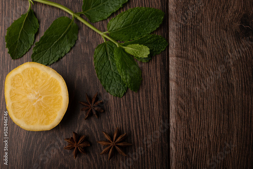 Fototapeta Naklejka Na Ścianę i Meble -  Lemon, mint and star anise on a dark wood background with copy space