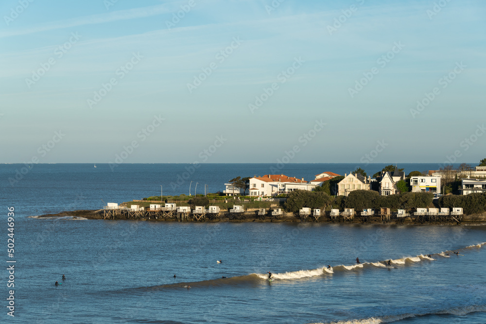 Royan, Charente-Maritime. Surfeurs au petit matin devant les carrelets et maisons typiques de la région