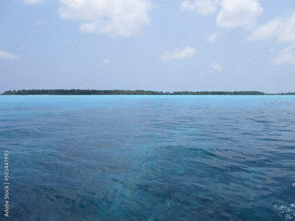 Maldives. Brown algae can be seen through the turquoise water. Blue sky, clear water and white sand. Paradise corner.