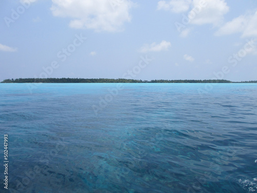 Maldives. Brown algae can be seen through the turquoise water. Blue sky, clear water and white sand. Paradise corner.
