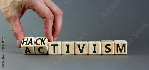 Activism or hacktivism symbol. Businessman turns wooden cubes and changes the word Activism to Hacktivism. Beautiful grey table grey background, copy space. Business activism or hacktivism concept. photo