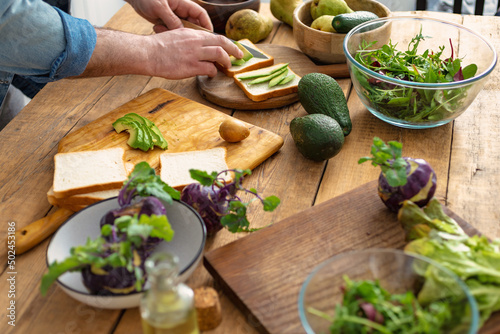 Man preparing avocado sandwiches at home kitchen. Cooking a healthy and tasty breakfast or lunch