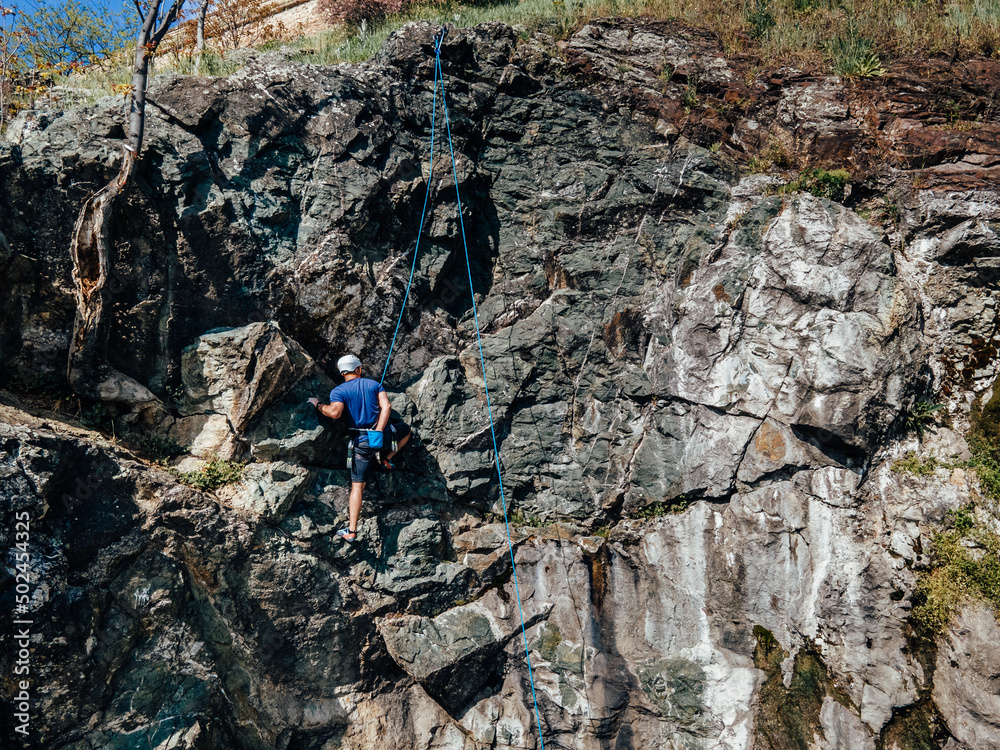 Man doing an activity, climbing on the rock, going to the top.