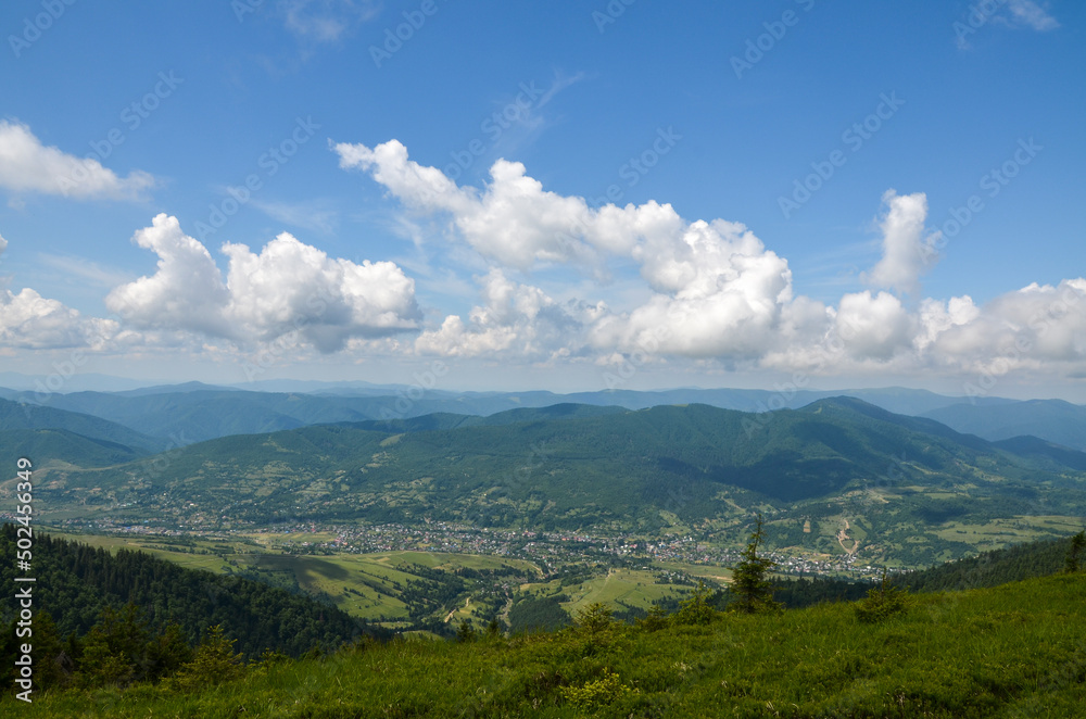 Scenic view of a village located in a valley between green mountains on a summer day. Carpathian Mountains, Ukraine