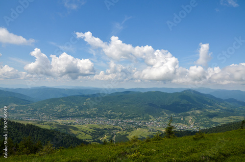 Scenic view of a village located in a valley between green mountains on a summer day. Carpathian Mountains, Ukraine