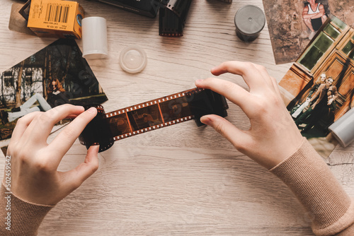 Old photo holding by a teenage girl, retro background with vintage camera, photos and film negative.
