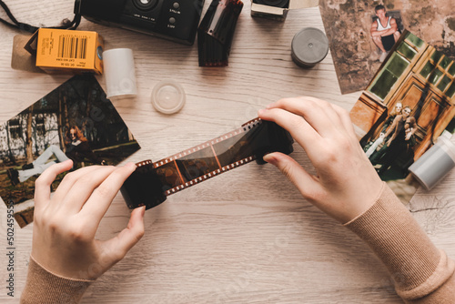 Old photo holding by a teenage girl, retro background with vintage camera, photos and film negative.
