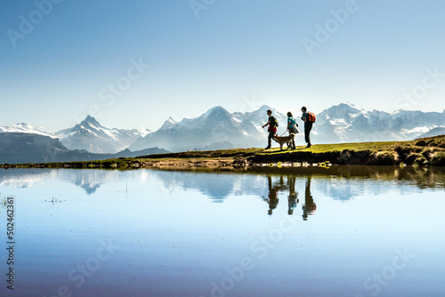 Wandern vor berühmter Gebirgskulisse, Eiger, Mönch und Jungfrau, berner Oberland, Schweiz
Wandergruppe mit Hund, gespiegelt in einem kleinen Bergsee