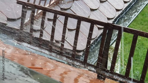 Close-up of a brown roof with snow guards and a gutter during a heavy thunderstorm with some hail falling down in springtime. Seen in Germany in May. photo