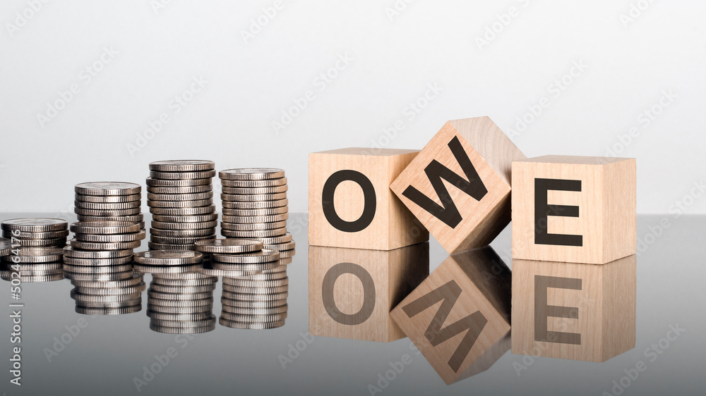 owe - text is made up of letters on wooden cubes lying on a mirror surface owe - text is made up of letters on wooden cubes lying on a mirror surface
