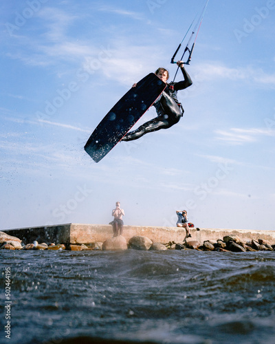 Man in wetsuit doing kiteboarding stunt in the water, Curonian lagoon, Lithuania photo