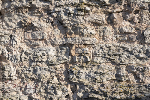 Fragment of an old dilapidated fortress wall. Limestone stone blocks cracked and partially collapsed. Background. Texture.