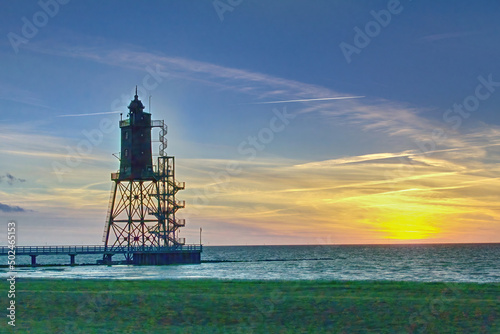 sunset at a lighthouse at low tide at north sea coast