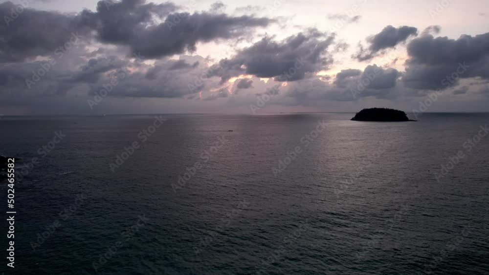 Beautiful sunset with clouds, sea and island. A small Thai ship is sailing. Clouds are reflected on the water. A lonely island stands in the distance. Top view from a drone. Calm ocean at sunset Beautiful sunset with clouds, sea and island. A small Thai ship is sailing. Clouds are reflected on the water. A lonely island stands in the distance. Top view from a drone. Calm ocean at sunset