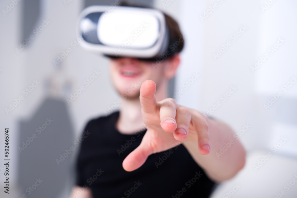 Portrait of happy young handsome man, positive smiling guy using, wearing a modern device virtual reality headset mask or 3D, AR, VR glasses, playing the game. People and technology metaverse concept