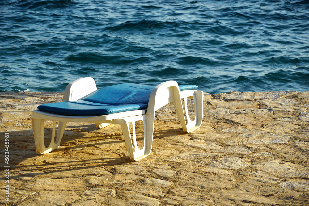 Sun lounger on the beach by the blue sea is reminiscent of a summer vacation Sun lounger on the beach by the blue sea is reminiscent of a summer vacation