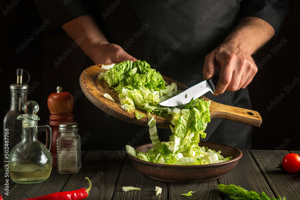 Chef while working in the restaurant kitchen. Diet breakfast or dinner idea. Napa cabbage salad preparation Chef while working in the restaurant kitchen. Diet breakfast or dinner idea. Napa cabbage salad preparation