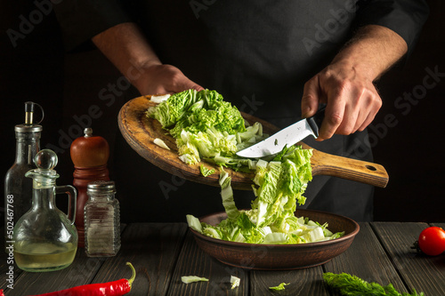 Chef while working in the restaurant kitchen. Diet breakfast or dinner idea. Napa cabbage salad preparation