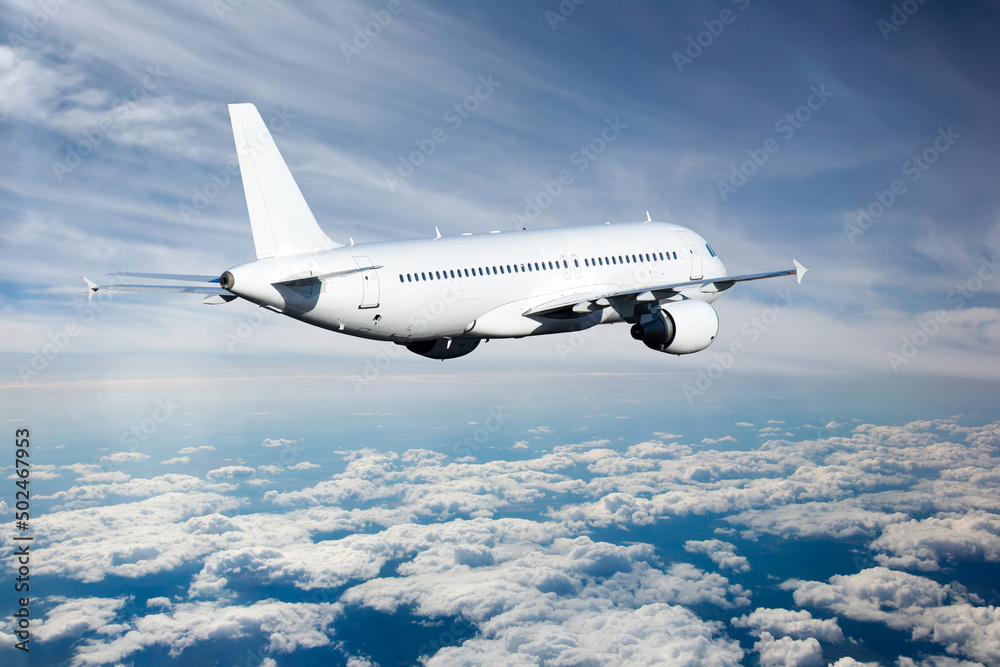 White passenger plane in flight above the clouds. Aircraft fly away. Back view of aircraft.