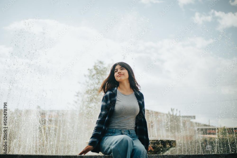 Retrato de mujer contenta sentada al borde de una pileta en un parque. Concepto de Personas.