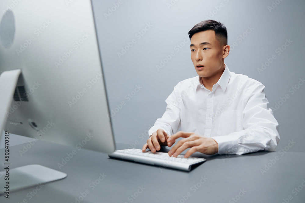 Asian man sits at a computer in the office with a keyboard Lifestyle work Asian man sits at a computer in the office with a keyboard Lifestyle work