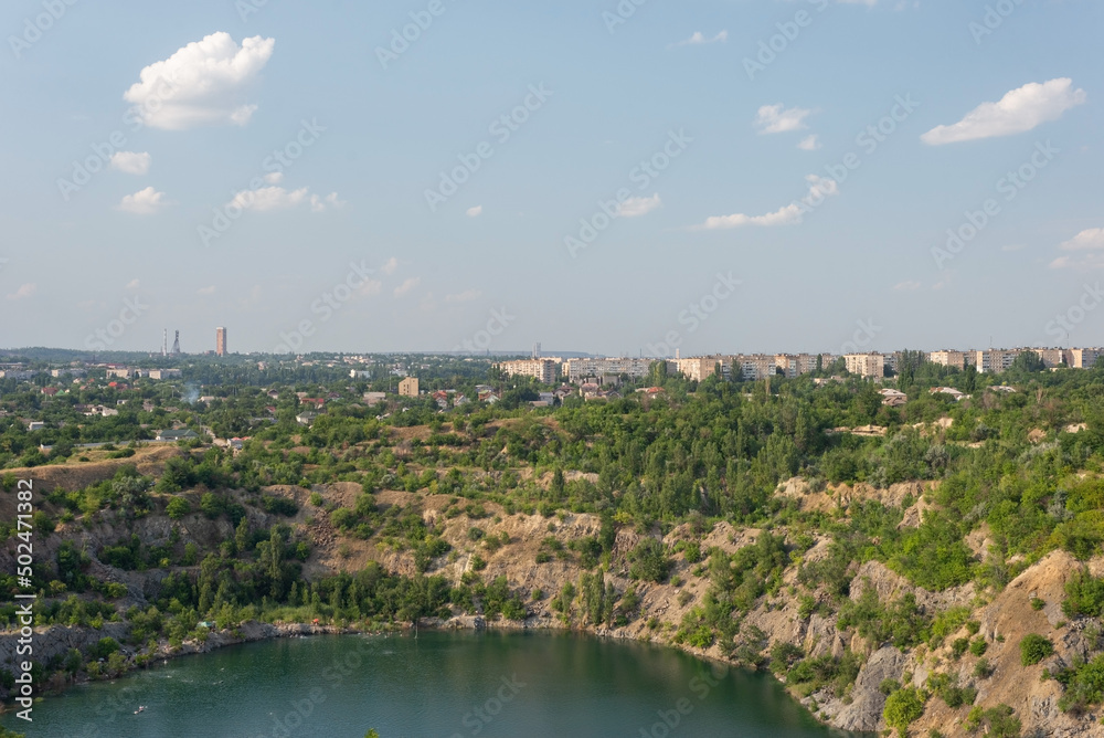 rocks of a flooded granite quarry on a background of cloudy sky
